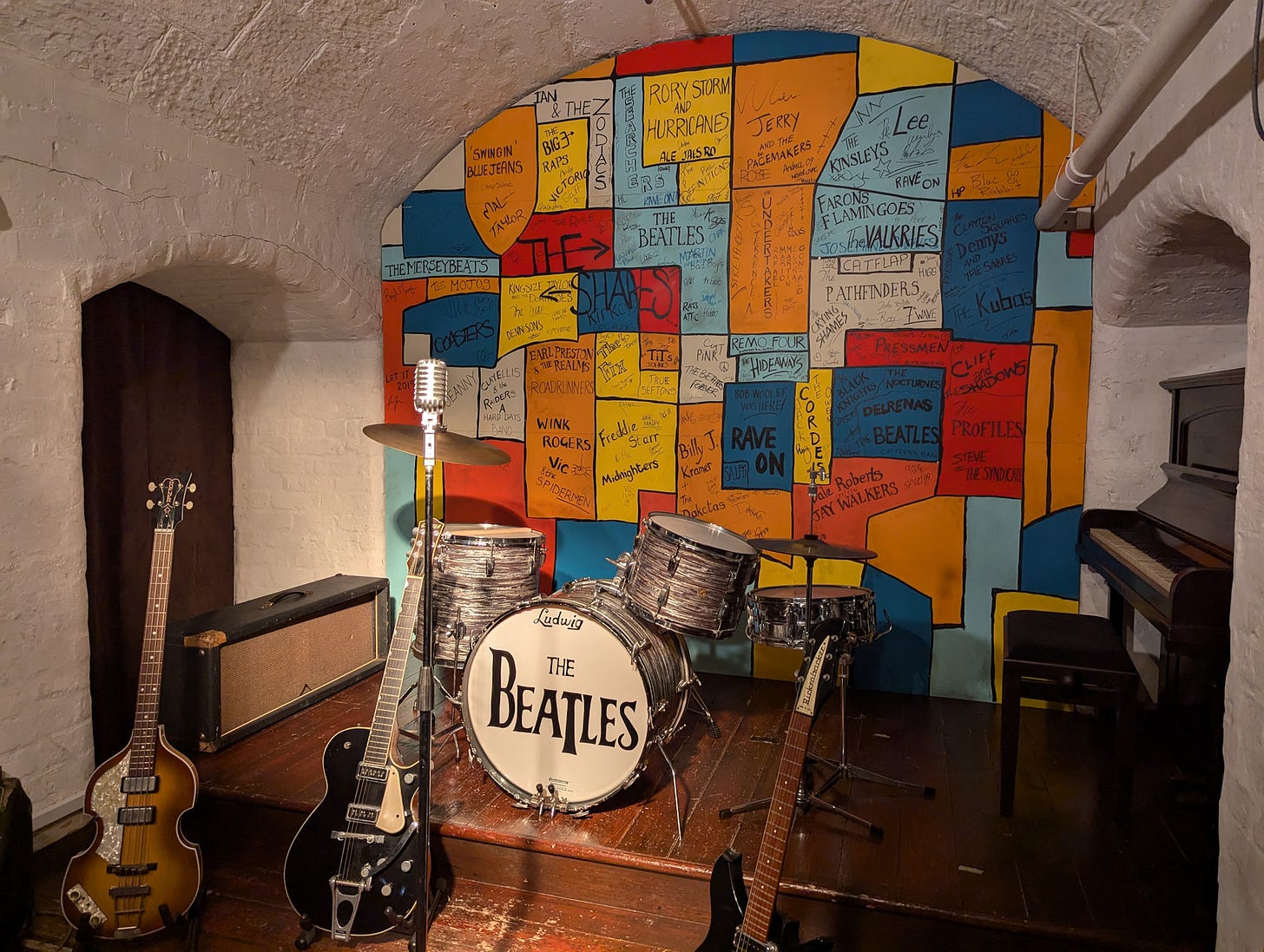 The small stage at the Cavern Club with guitars and drums. 