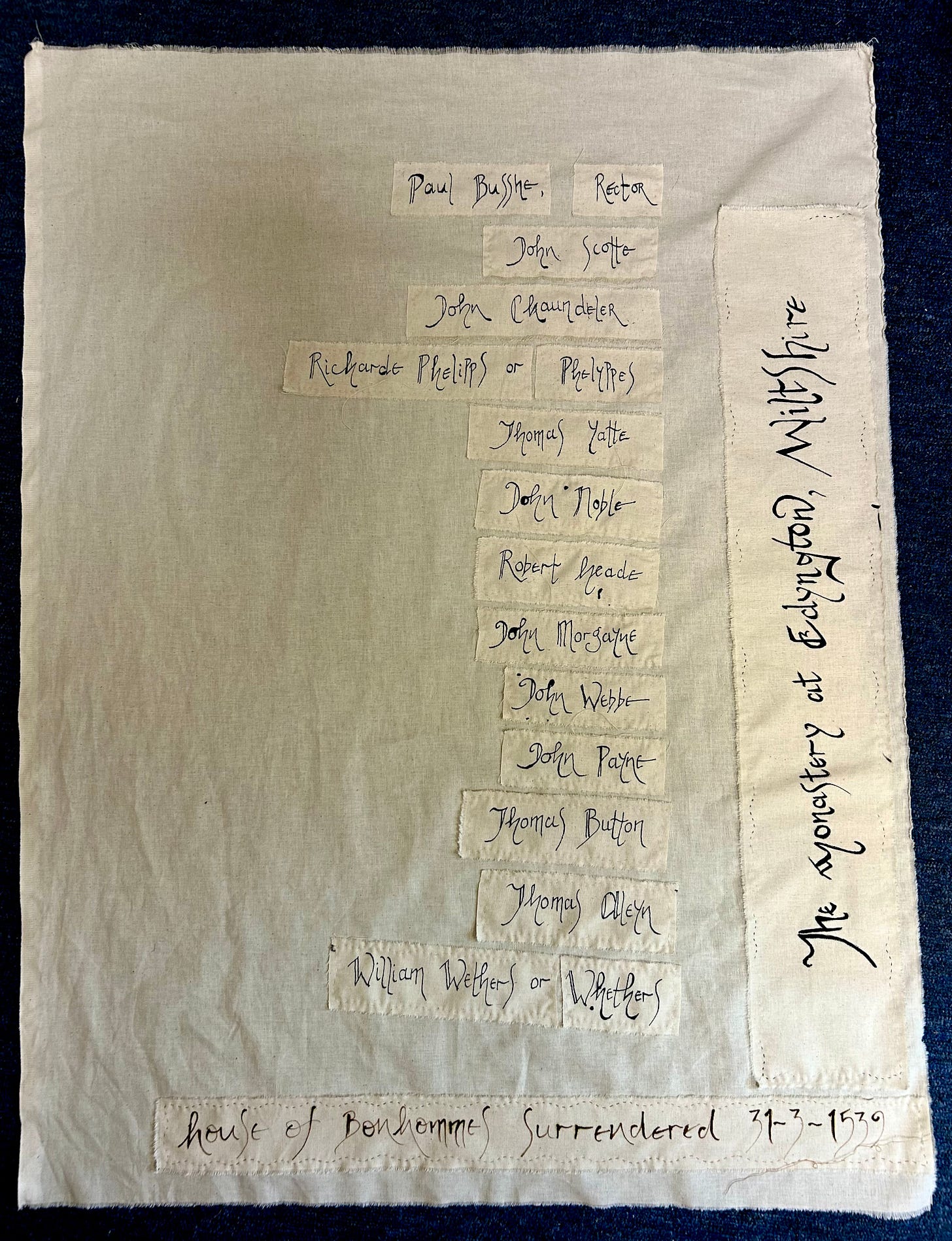 A large piece of calico with a list of names stitched onto it. The name The Monastery of Edyngton is stitched down the right hand side. The bottom of the piece notes that the monastery was surrendered on 31.3.1539, and that it was a house of Bonhommes. A large piece of calico with a list of names stitched onto it. The name The Monastery of Edyngton is stitched down the right hand side. The bottom of the piece notes that the monastery was surrendered on 31.3.1539, and that it was a house of Bonhommes.
