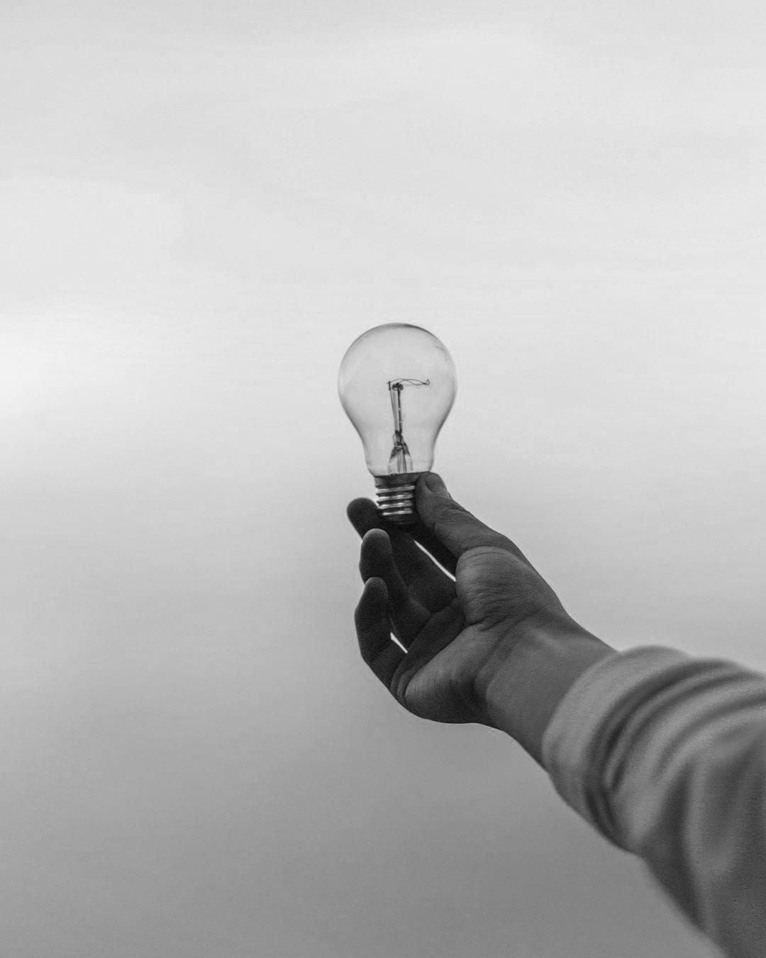 person holding light bulb person holding light bulb