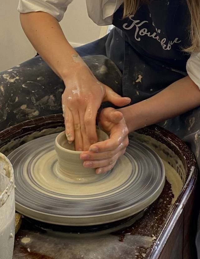 This may contain: a woman is making a bowl on a potter's wheel with her hands in it