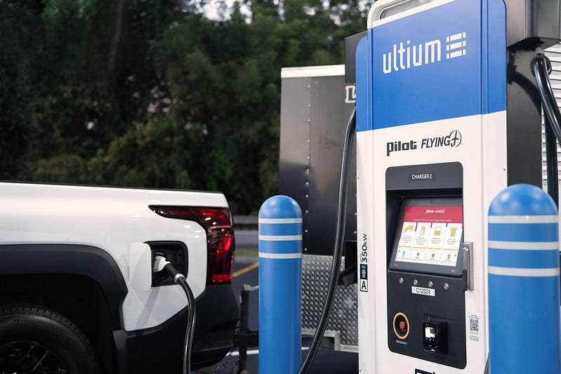 A white Chevy Silverado EV pickup (or a CGI render of one) charging at a Pilot/Flying J charging station. A white Chevy Silverado EV pickup (or a CGI render of one) charging at a Pilot/Flying J charging station.