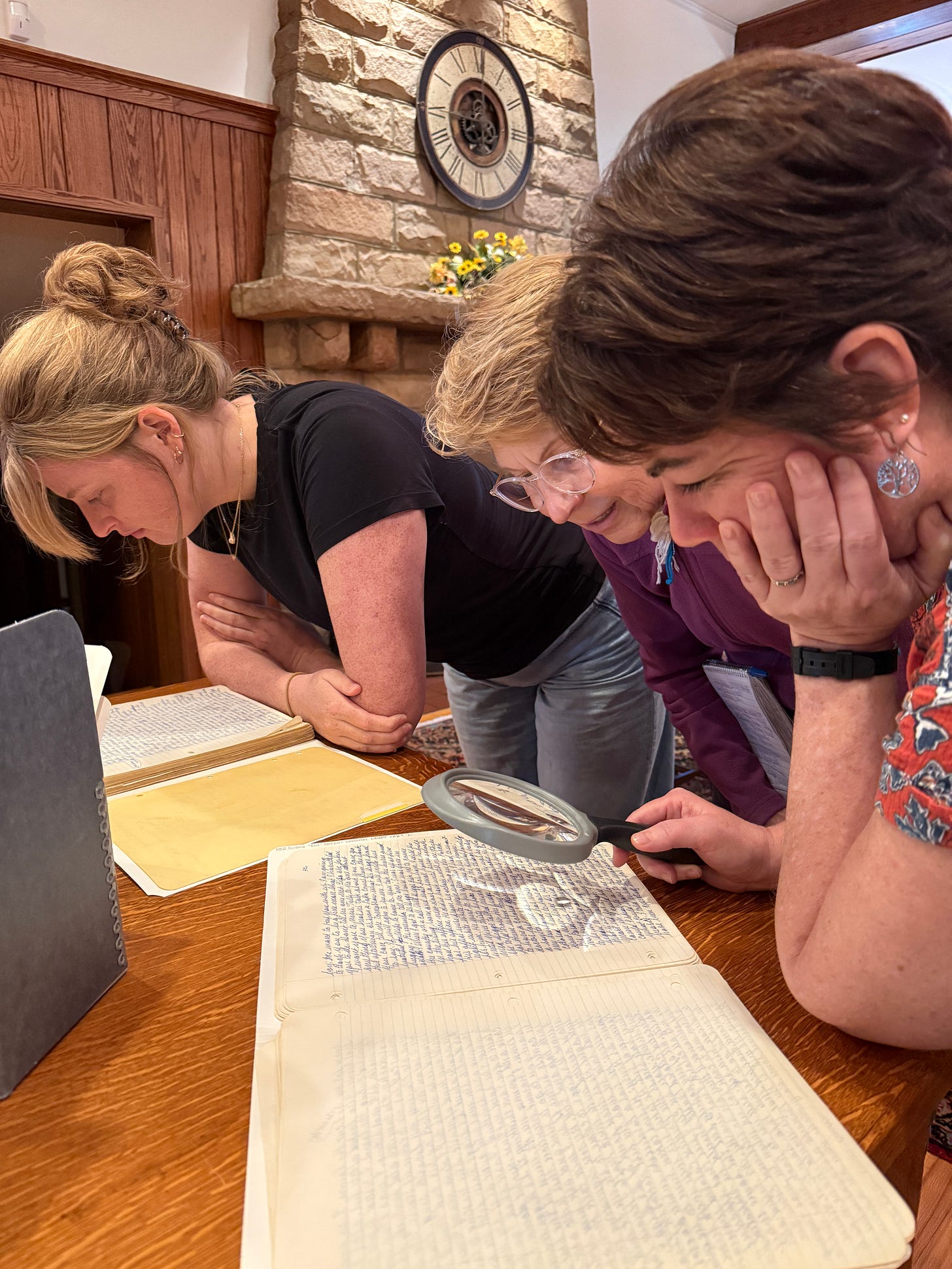 Students lean over manuscript with magnifying glass