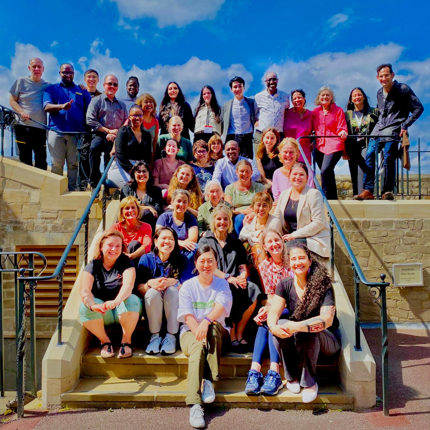A group photo of Roots&Shoots coordinators from 40+ country with Dr. Jane Goodall gathered at the Windsor Castle. July 2024
