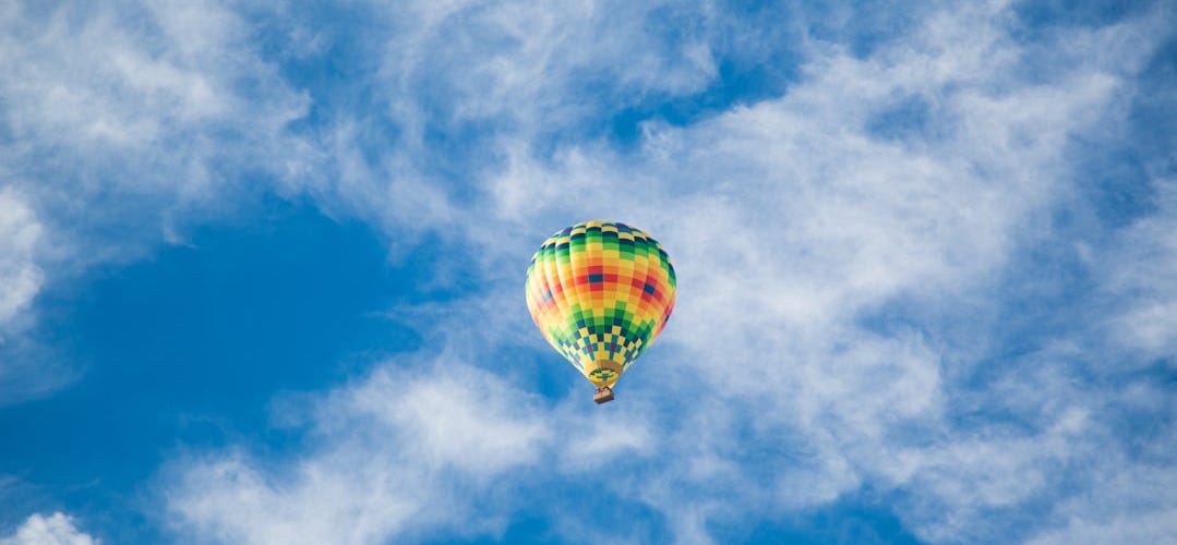 yellow, green, and black hot air balloon on sky yellow, green, and black hot air balloon on sky