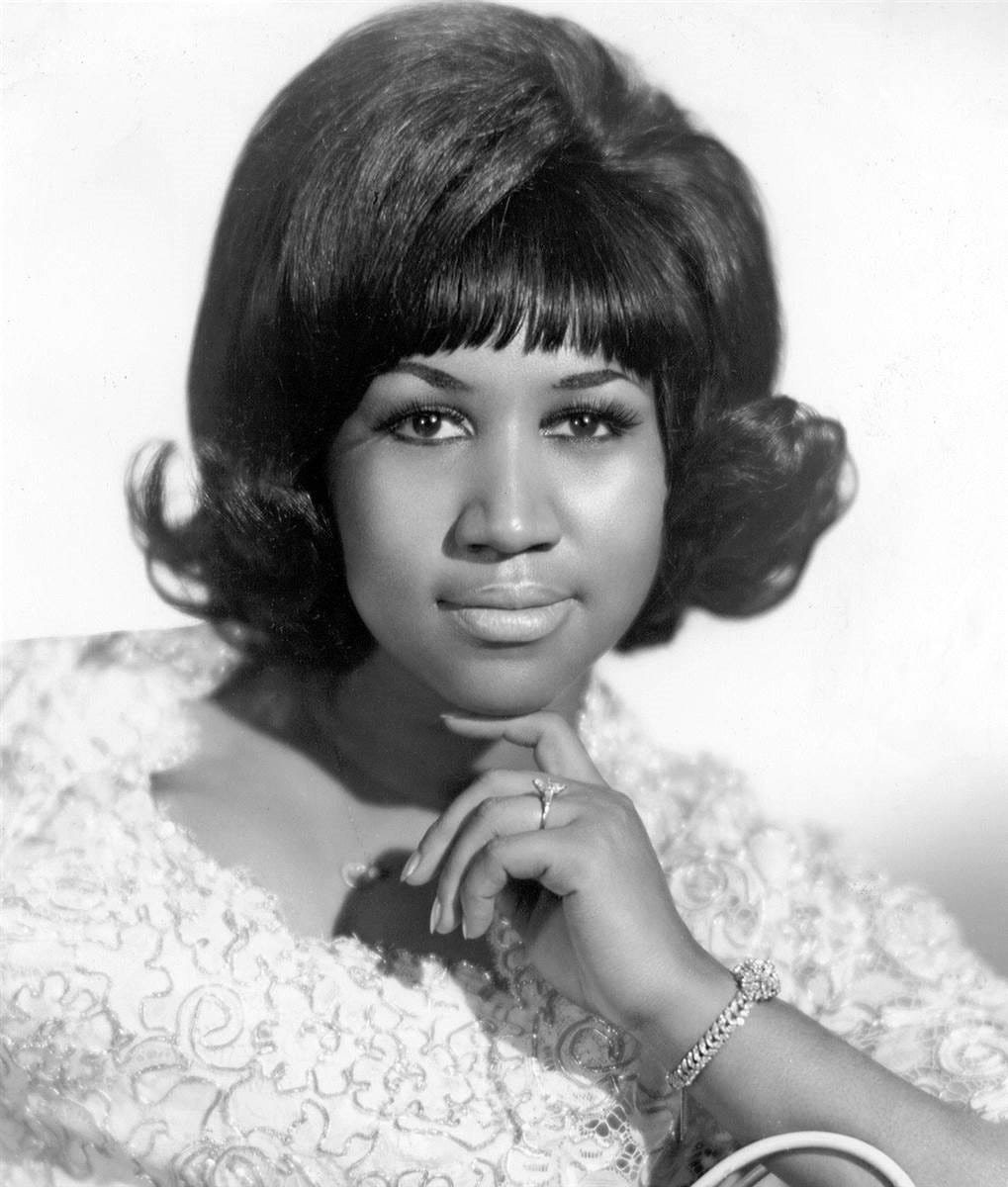 Franklin, with a lacy white dress and perfectly coiffed hair, rests her chin on her index finger and poses, looking straight into the camera. Franklin, with a lacy white dress and perfectly coiffed hair, rests her chin on her index finger and poses, looking straight into the camera.