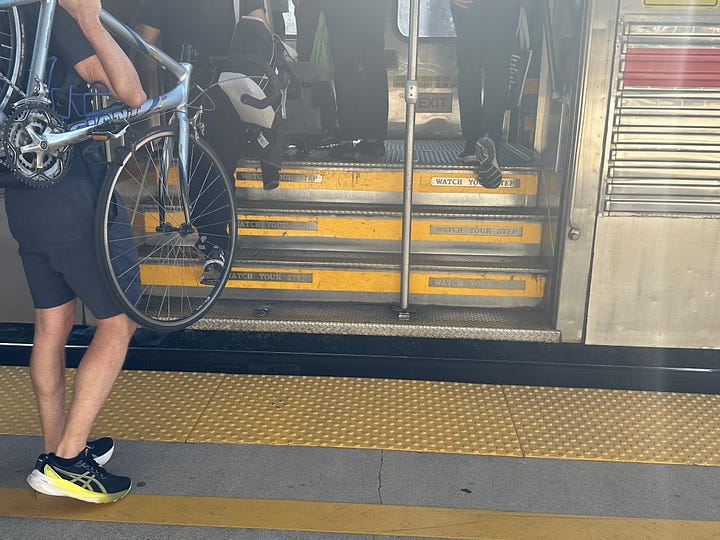 Photograph showing the doors of a train. The doors are open. The emphasis is on the stairs of the train. The old train has multiple steps and a large gap between the platform and the train. The newer train shows a much smaller gap and a low floor, single step entrance of the train.