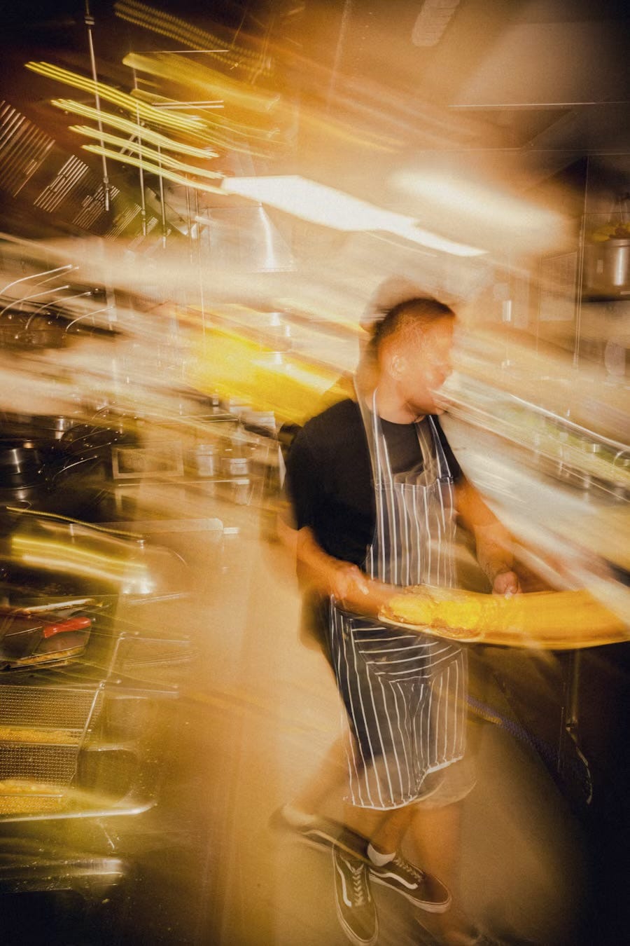 Blurred image of a kitchen worker, mostly streaked yellow lights. Blurred image of a kitchen worker, mostly streaked yellow lights.