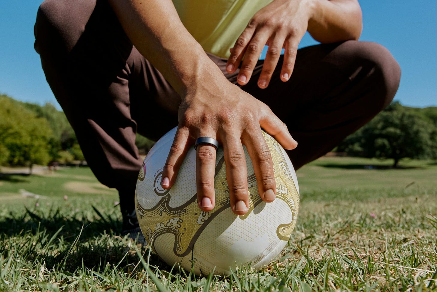 Hand on top of a soccer ball wearing an Oura Ring Hand on top of a soccer ball wearing an Oura Ring