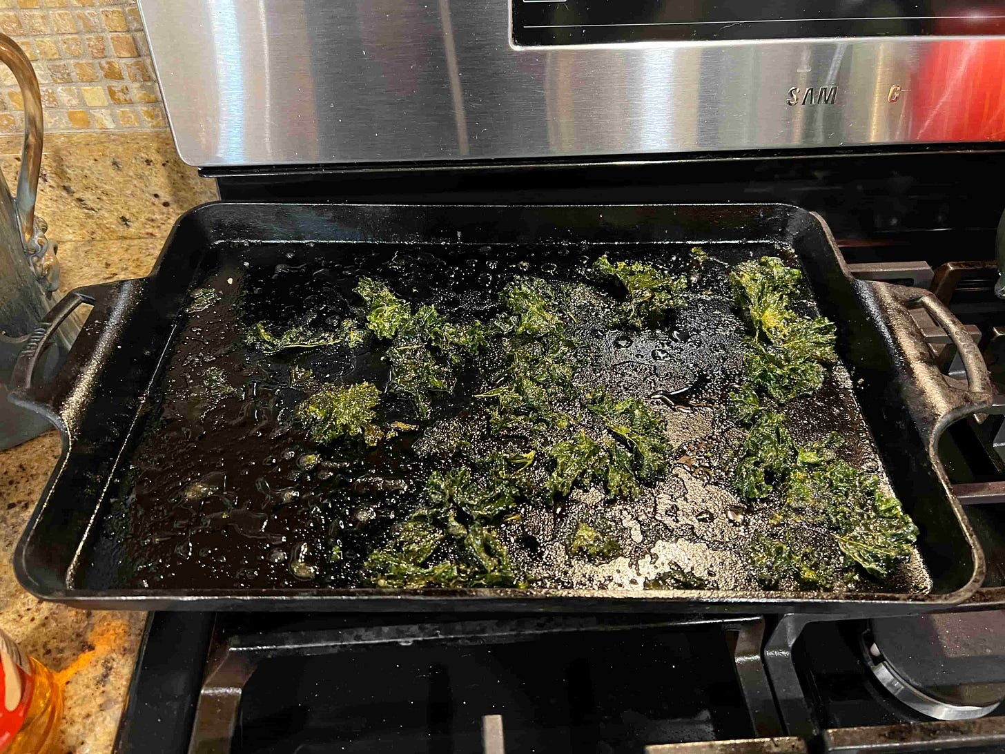 photo of an almost-empty baking sheet showing only a few remaining kale chips photo of an almost-empty baking sheet showing only a few remaining kale chips