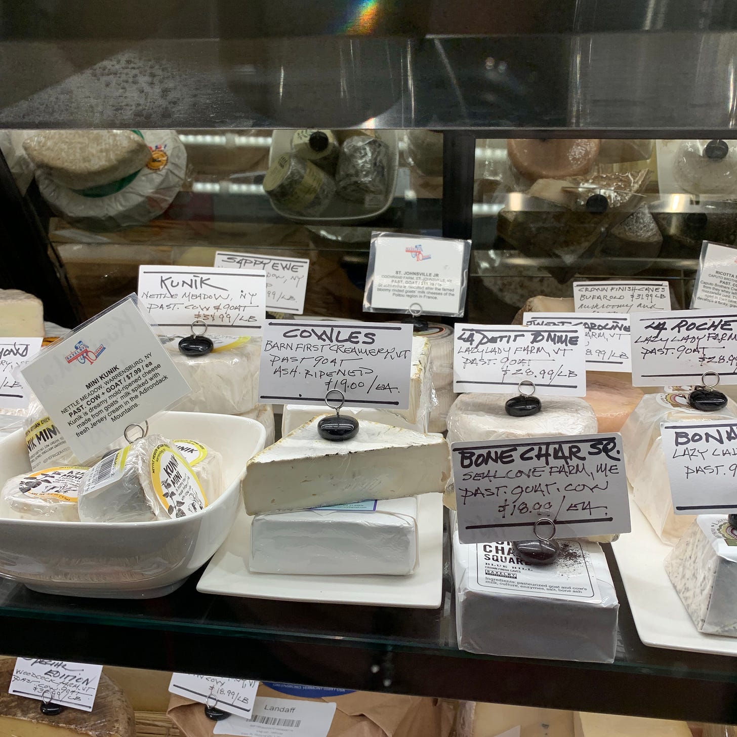 a selection of soft cheeses in a cheese case
