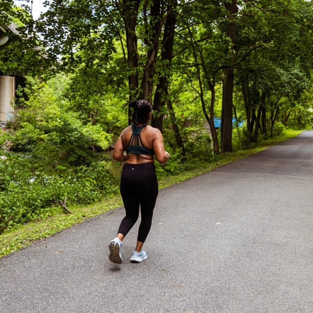 A person jogging on a pathway surrounded by greenery near a bridge. A person jogging on a pathway surrounded by greenery near a bridge.