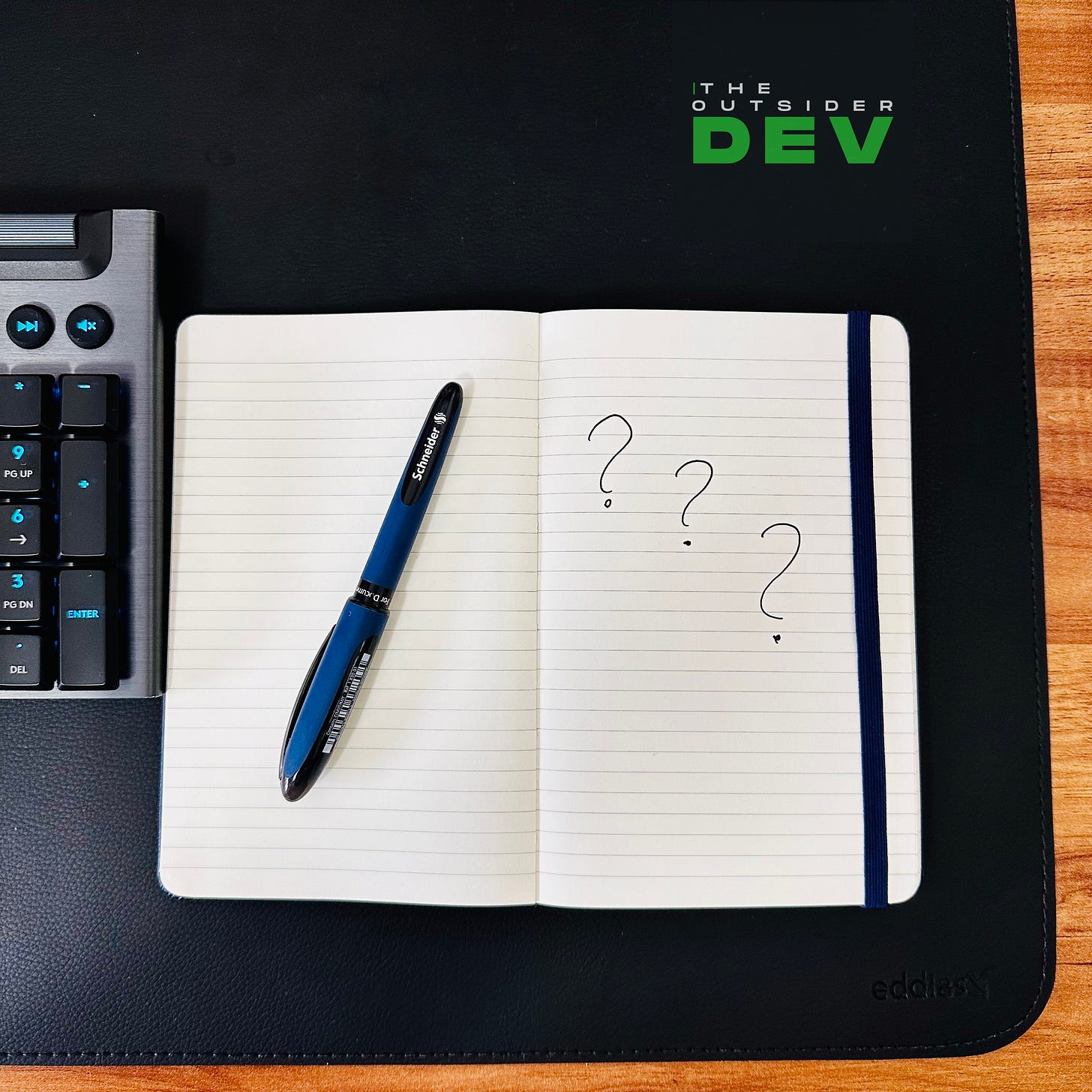 Notebook with question marks next to a keyboard