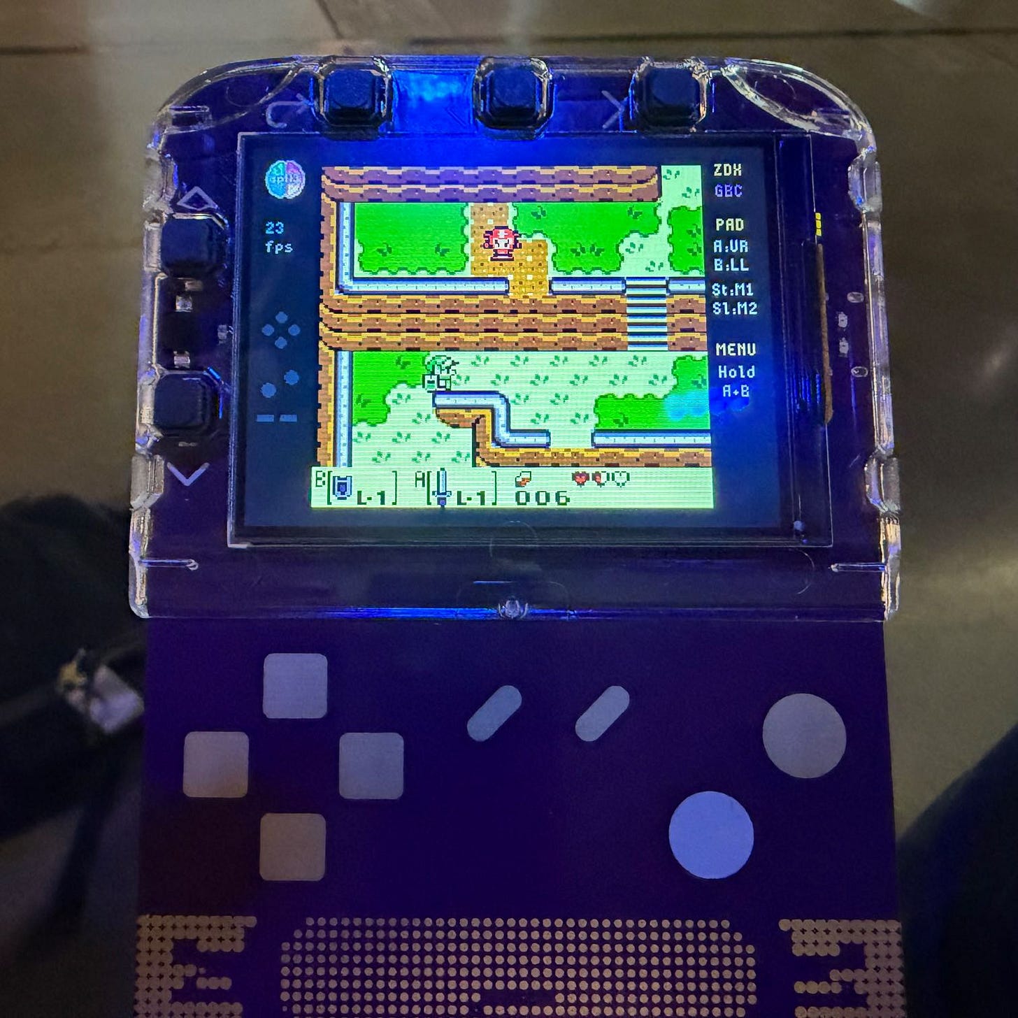 Photo of the badge running Zelda, in full color, with visible touch buttons below the screen.