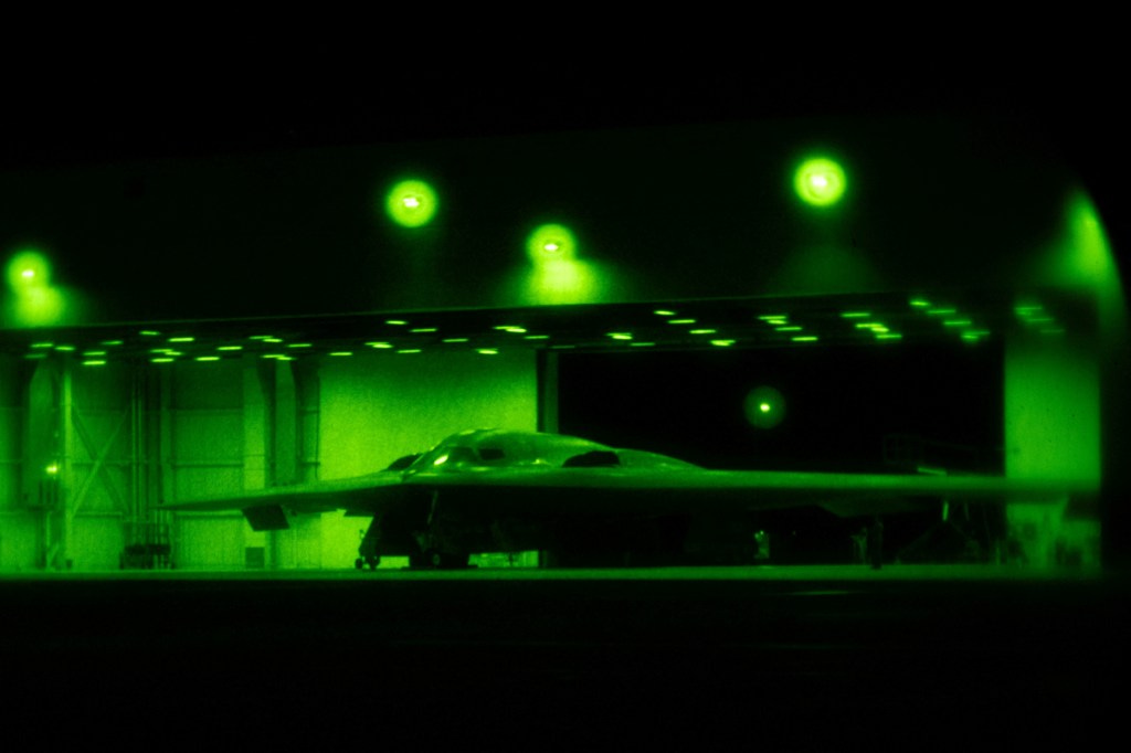 Night vision image of a B-2 Spirit stealth bomber in a hangar.