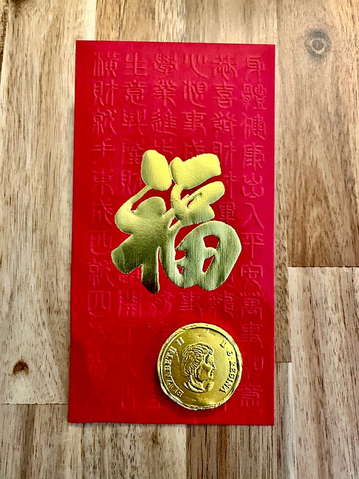Left: cookie in shape of Chinese red lantern, with word for 'prosperity' written in Chinese. Right: Chinese red packet and gold coin to celebrate Lunar New Year.