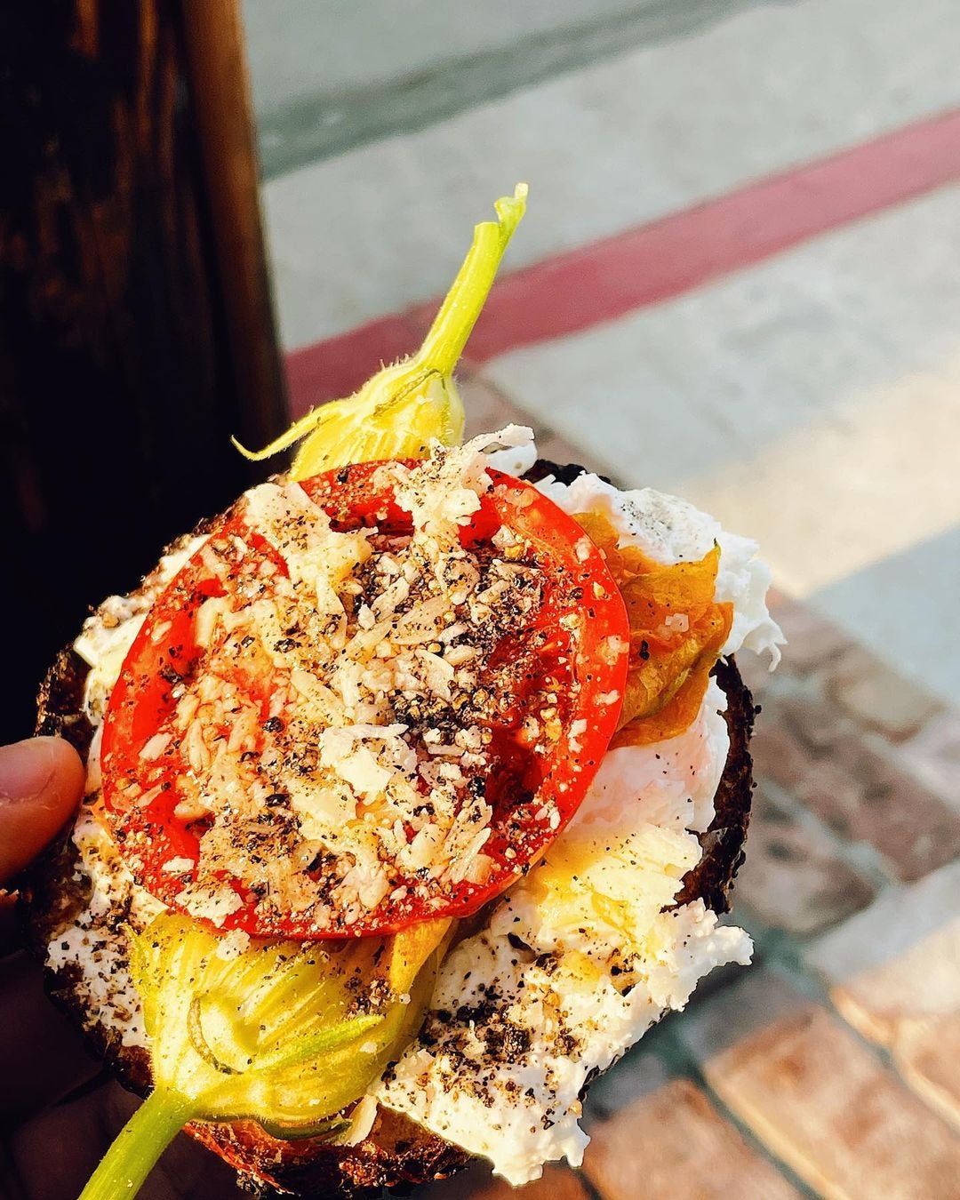bagel with burrata cheese, pepper, olive oil, squash blossom, tomato, parm and salt