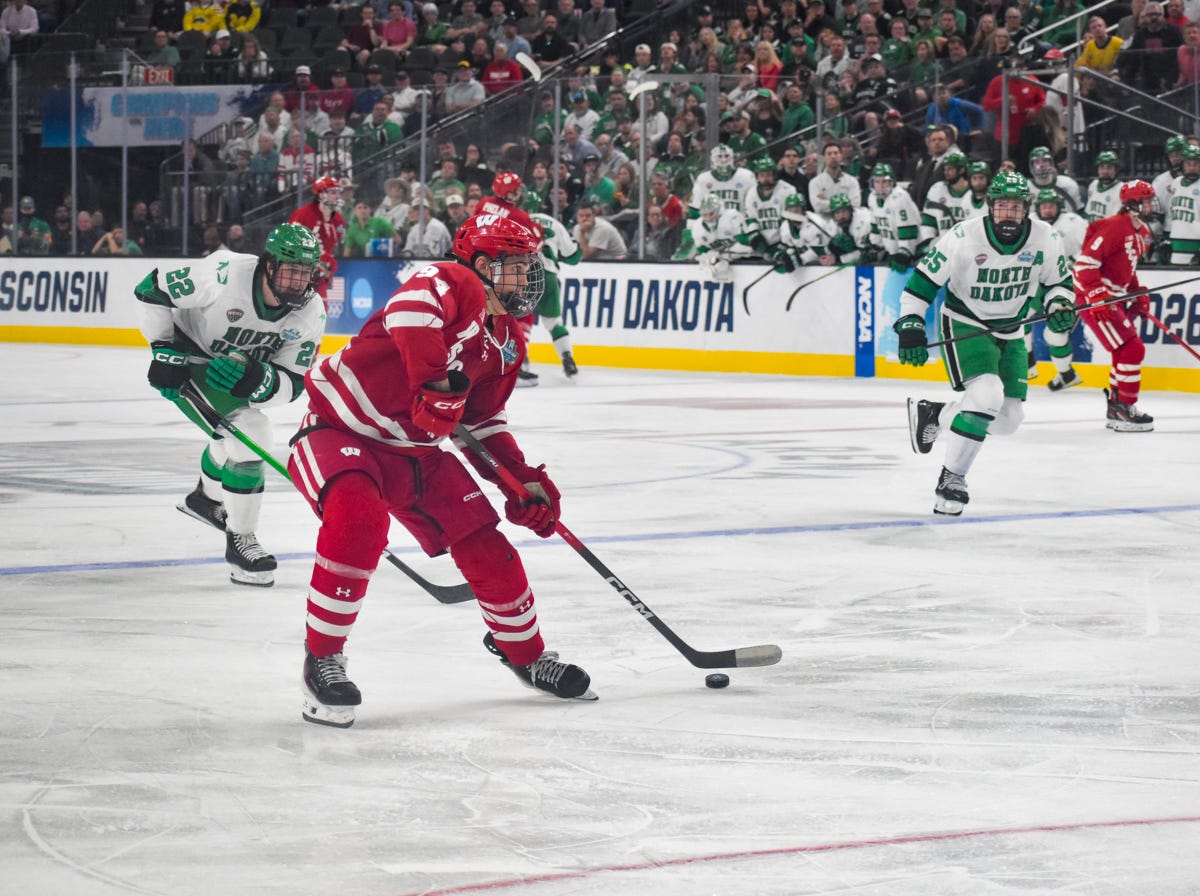 Wisconsin hockey center Vasily Zelenov enters the offensive zone and carries the puck near the top of the right faceoff circle