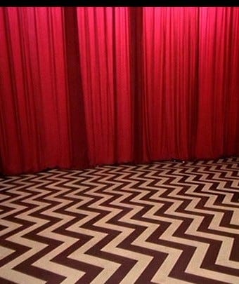 A red curtain and a chevron pattern floor
Description automatically generated