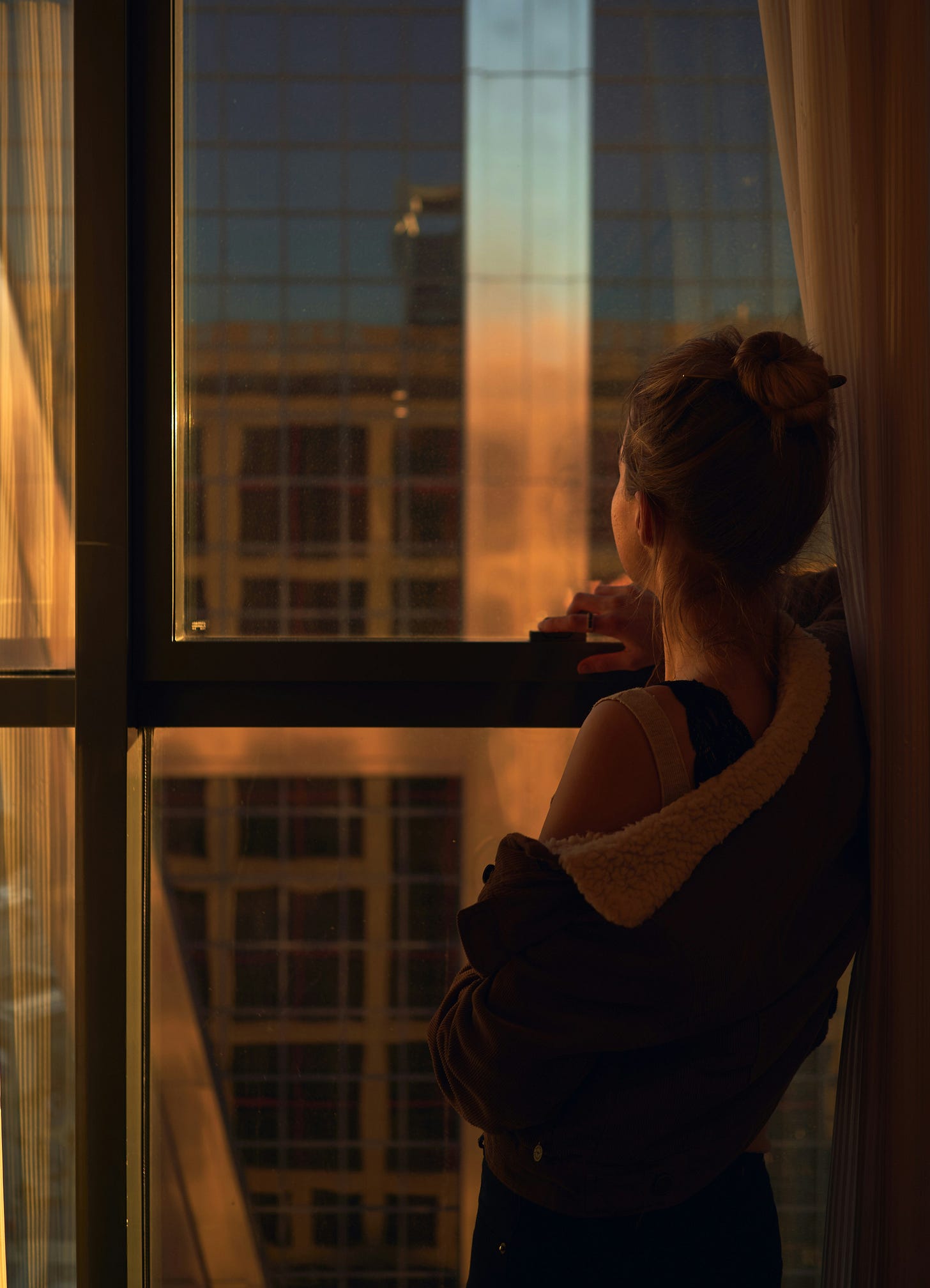 Woman in black sweater standing beside glass window
