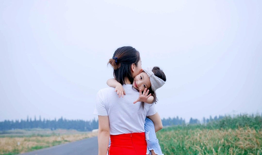 a woman holding a child on her back on a road