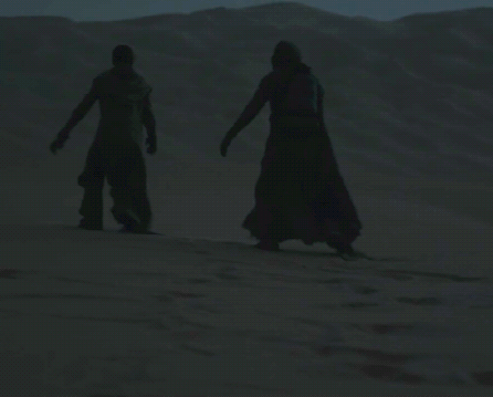 a couple of people standing in the desert holding hands