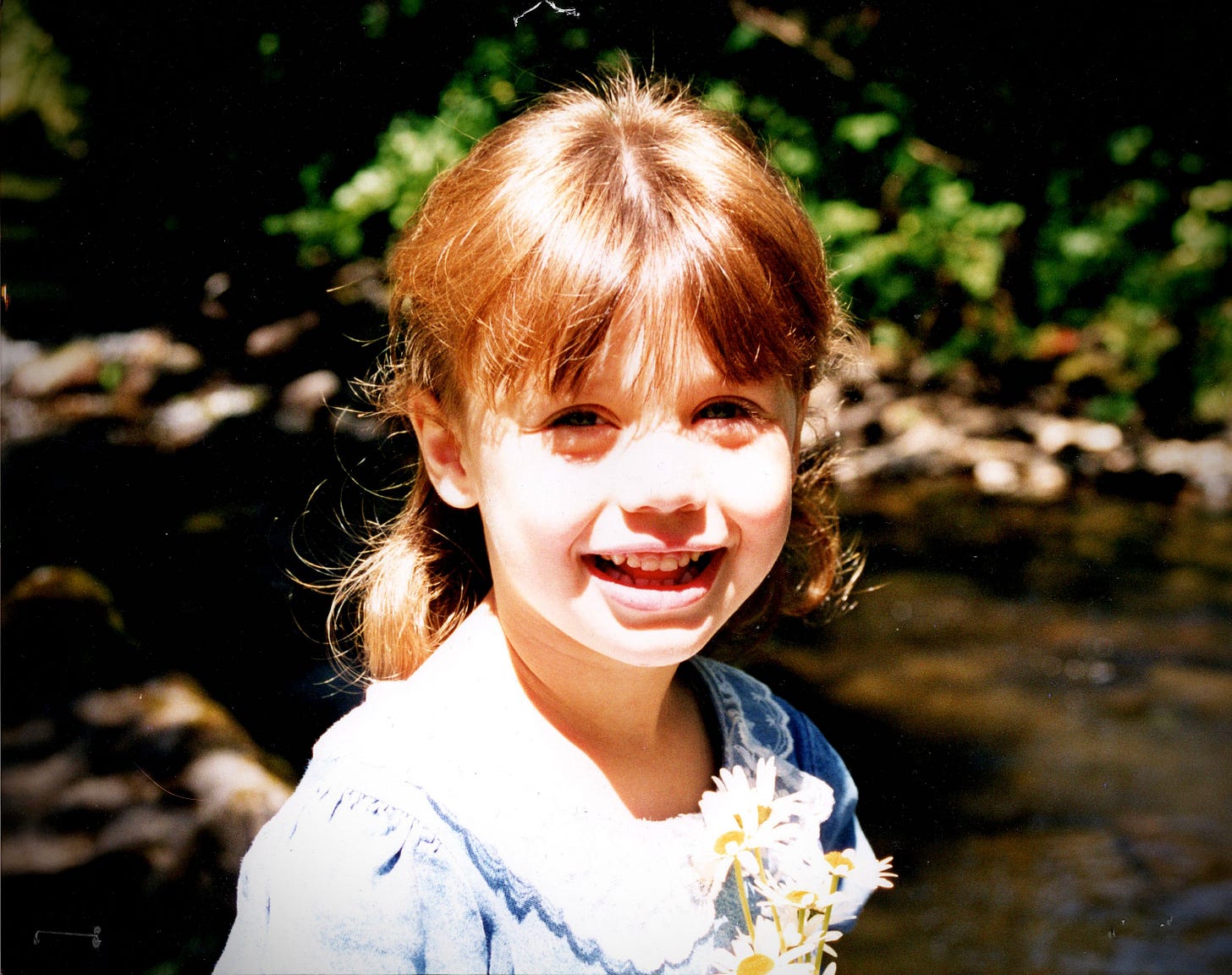 Substack post Grape cover Image of a small girl holding flowers smiling looking at a camera Substack post Grape cover Image of a small girl holding flowers smiling looking at a camera