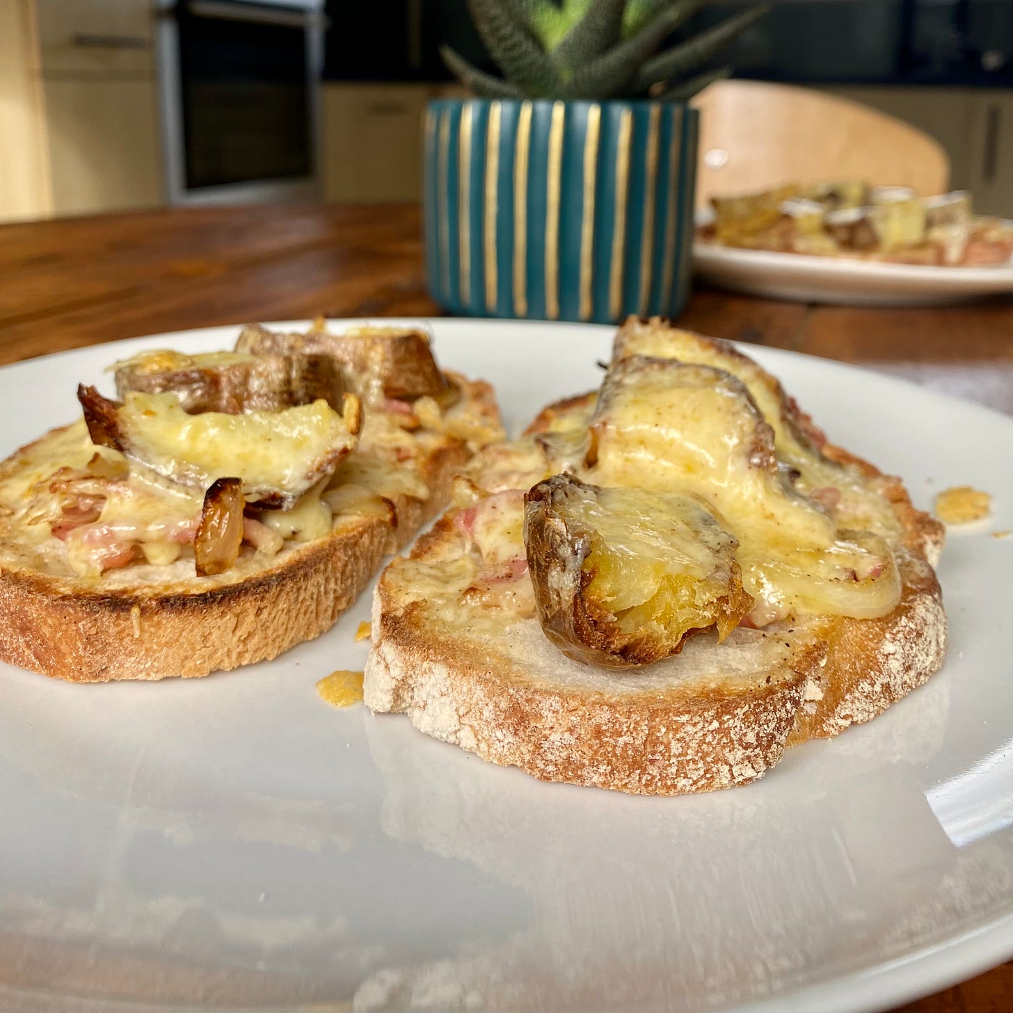 White plate topped with two pieces of toast, covered in bacon, onion, potato and cheese