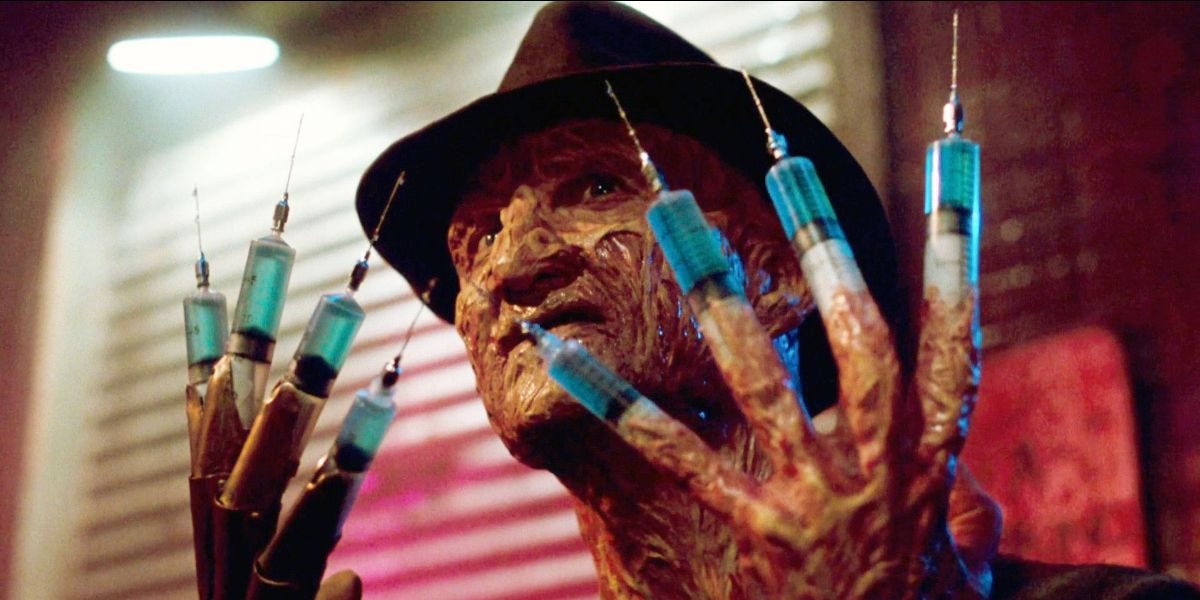 The disfigured face of Freddy Kruger wearing a fedora holds up ten fingers that have been transformed into hypodermic syringes full of blue liquid. 