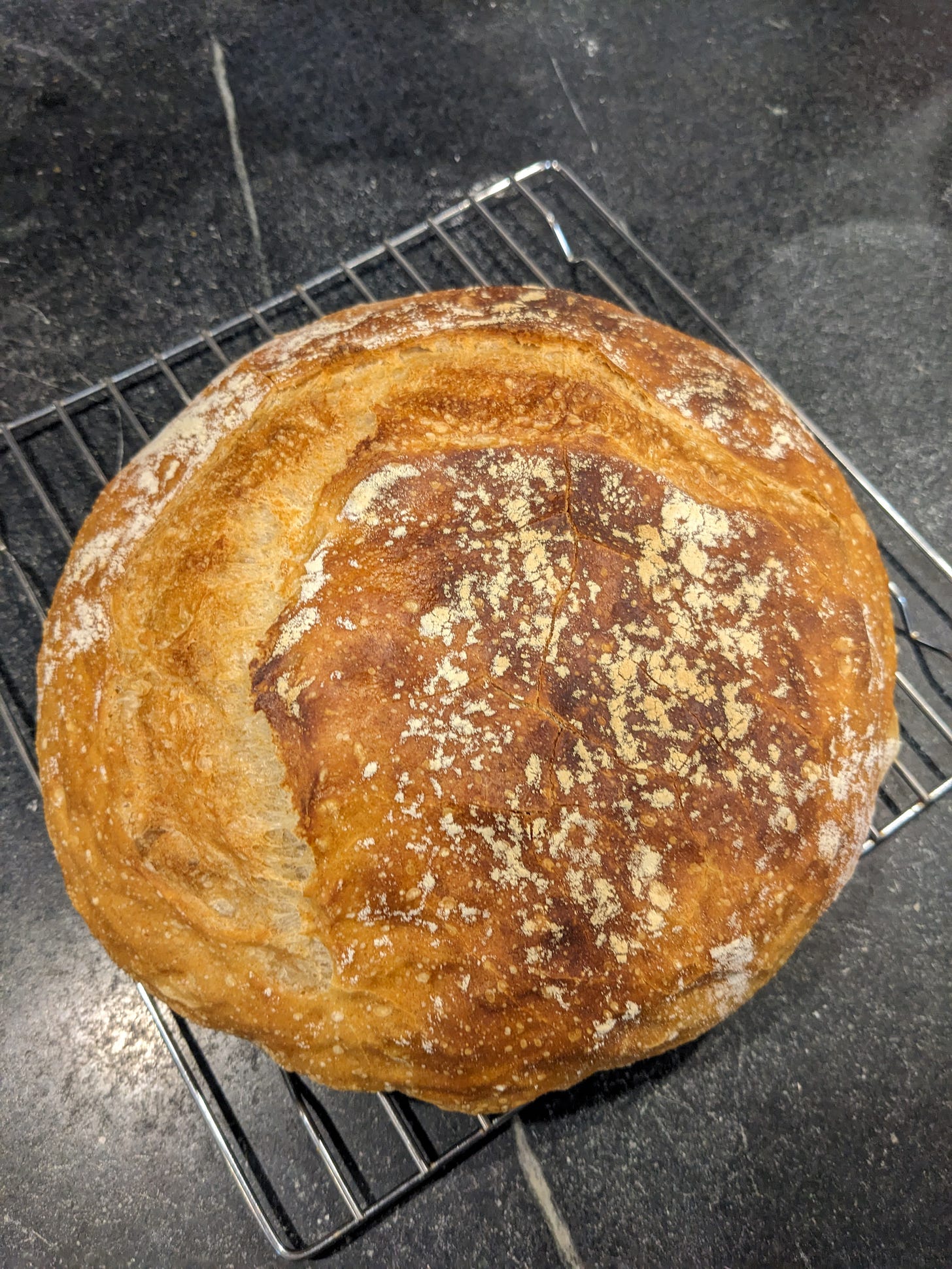 A boule of home-baked bread on a cooling rack.