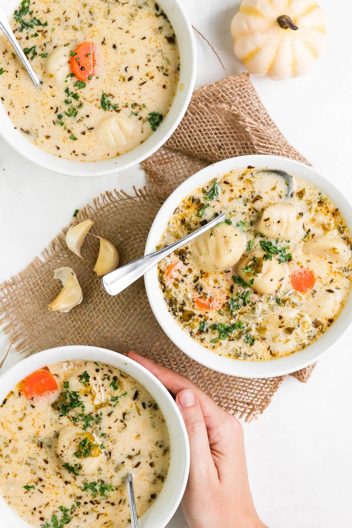 three white bowls of soup with spoons.