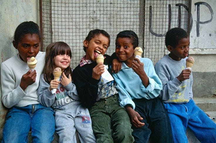 This may contain: four children sitting on steps eating ice cream and one boy is holding an ice cream cone
