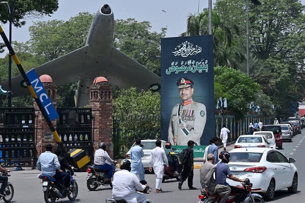 A billboard next to a city street shows a military man in uniform, and behind it is a display of a fighter jet. A billboard next to a city street shows a military man in uniform, and behind it is a display of a fighter jet.