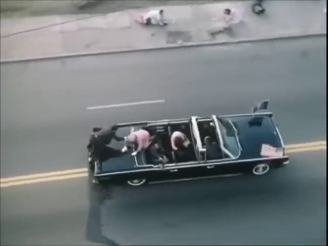 Jackie climbs over the back of the car; Clint Hill climbs over the back of the car in the other direction.