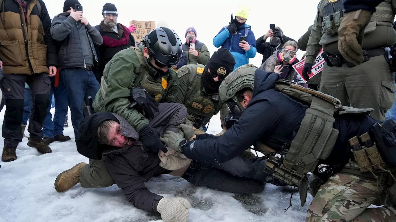 Three ICE agents pin a man to the frozen ground in Minneapolis.