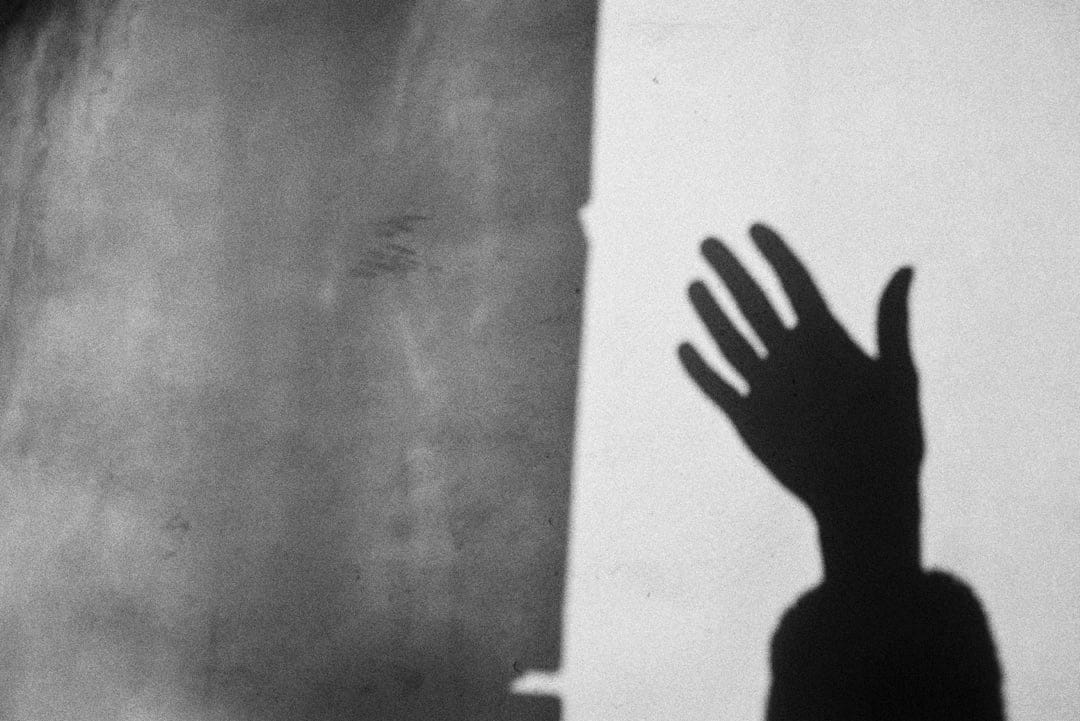 Shadow of a hand waving on a yellow wall