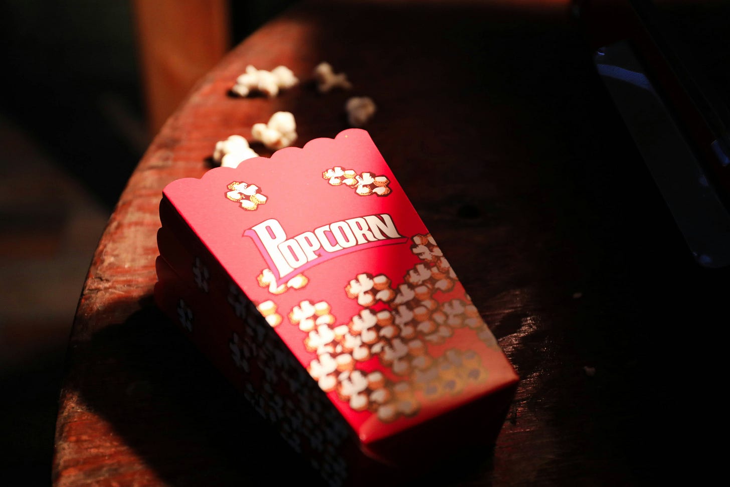 A bucket of popcorn spilled across a movie theater seat. A bucket of popcorn spilled across a movie theater seat.