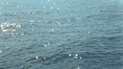 This may contain: the water is very blue and has little white dots on it's surface,