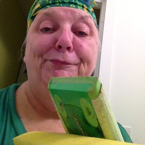 Photo of disgusted woman wearing a scarf on her head and carrying a Swiffer dustmop