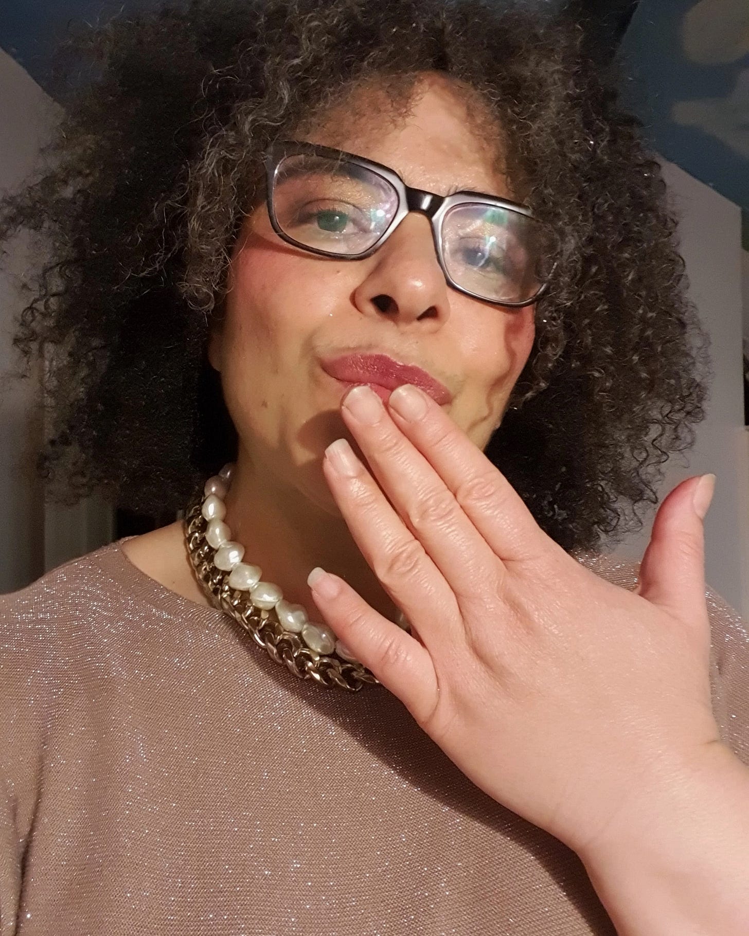 A woman wearing makeup looking at the camera and blowing a kiss