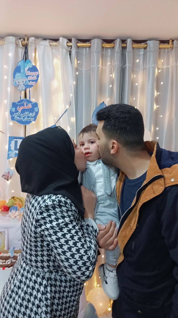 a couple kissing their son on his 1st bithday