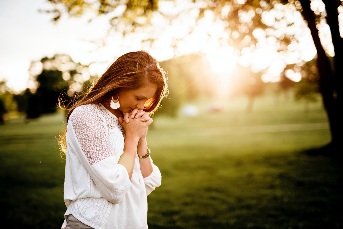 Woman praying beneath trees
