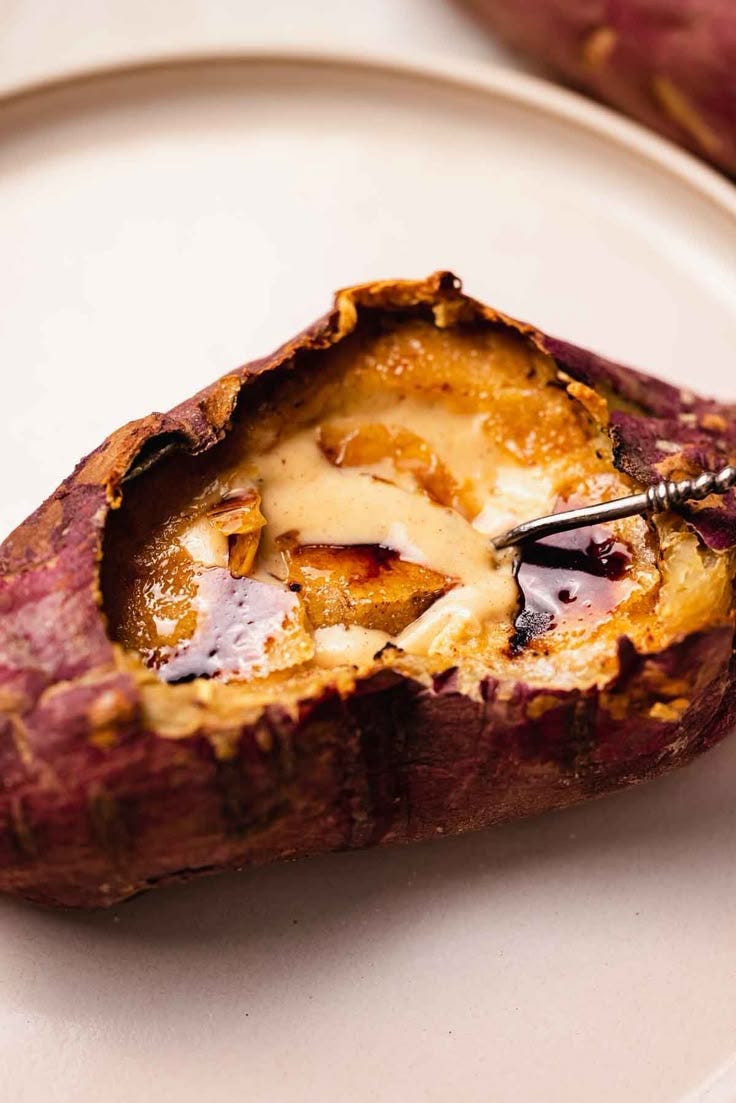 This may contain: a close up of a baked potato on a white plate with a fork in it