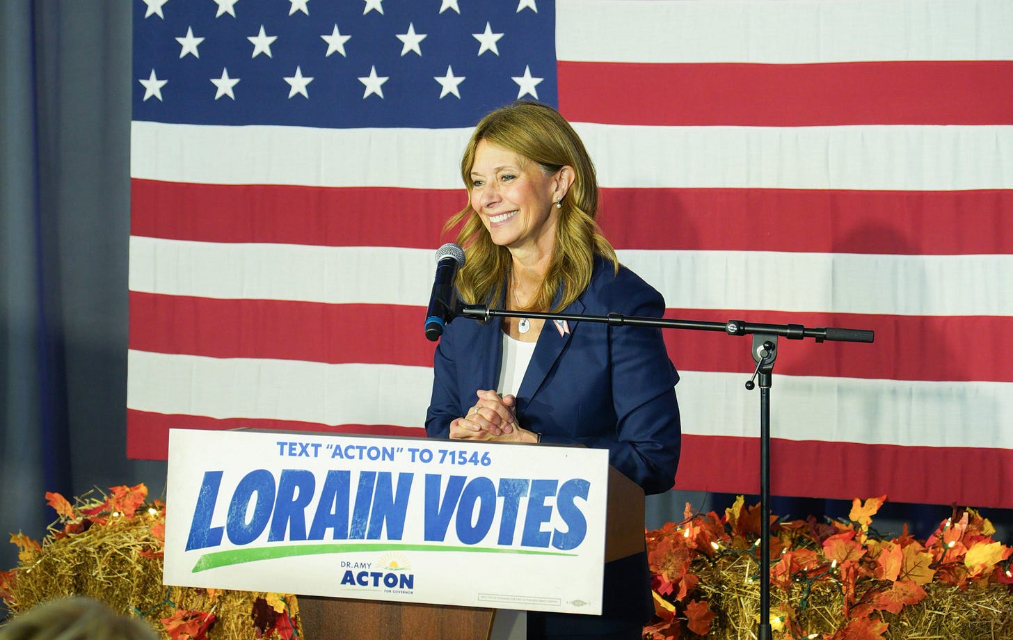 Amy Acton speaking in front of a US flag
