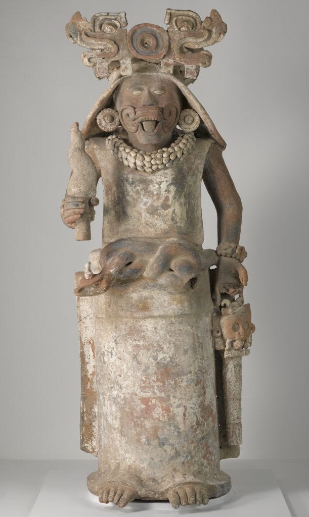 A sculpture of a female deity holding a torch in her right hand and a bag in her left hand. A sculpture of a female deity holding a torch in her right hand and a bag in her left hand.