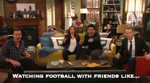 a group of people sitting on a couch watching a football game