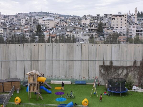 Jewish settlers who live in the Rachel's Tomb compound enjoy their playground located next to a section of Israel's concrete barrier, separating them from the West Bank city of Bethlehem in the background, Tuesday, March 8, 2022. Twenty years after Israel decided to built its controversial separation barrier amid a wave of Palestinian attacks, it remains in place, even as Israel encourages its own citizens to settle on both sides and admits tens of thousands of Palestinian laborers. (AP Photo/Oded Balilty) Jewish settlers who live in the Rachel's Tomb compound enjoy their playground located next to a section of Israel's concrete barrier, separating them from the West Bank city of Bethlehem in the background, Tuesday, March 8, 2022. Twenty years after Israel decided to built its controversial separation barrier amid a wave of Palestinian attacks, it remains in place, even as Israel encourages its own citizens to settle on both sides and admits tens of thousands of Palestinian laborers. (AP Photo/Oded Balilty)