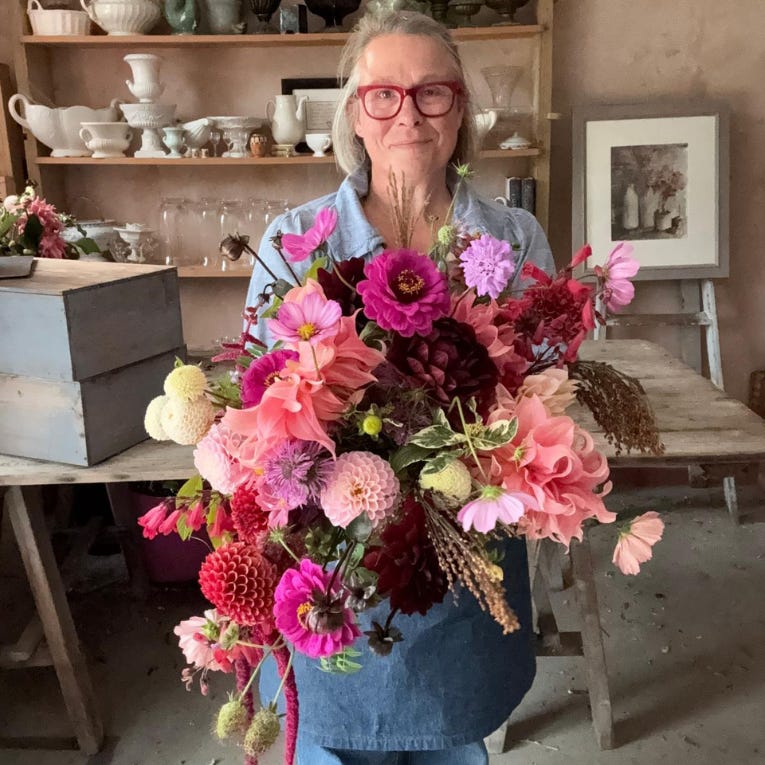 Flower farmer Georgie Newbery holds a gigantic hand tie bouquet mostly made up of pink, peach, purple and cream dahlias of all sizes and shapes