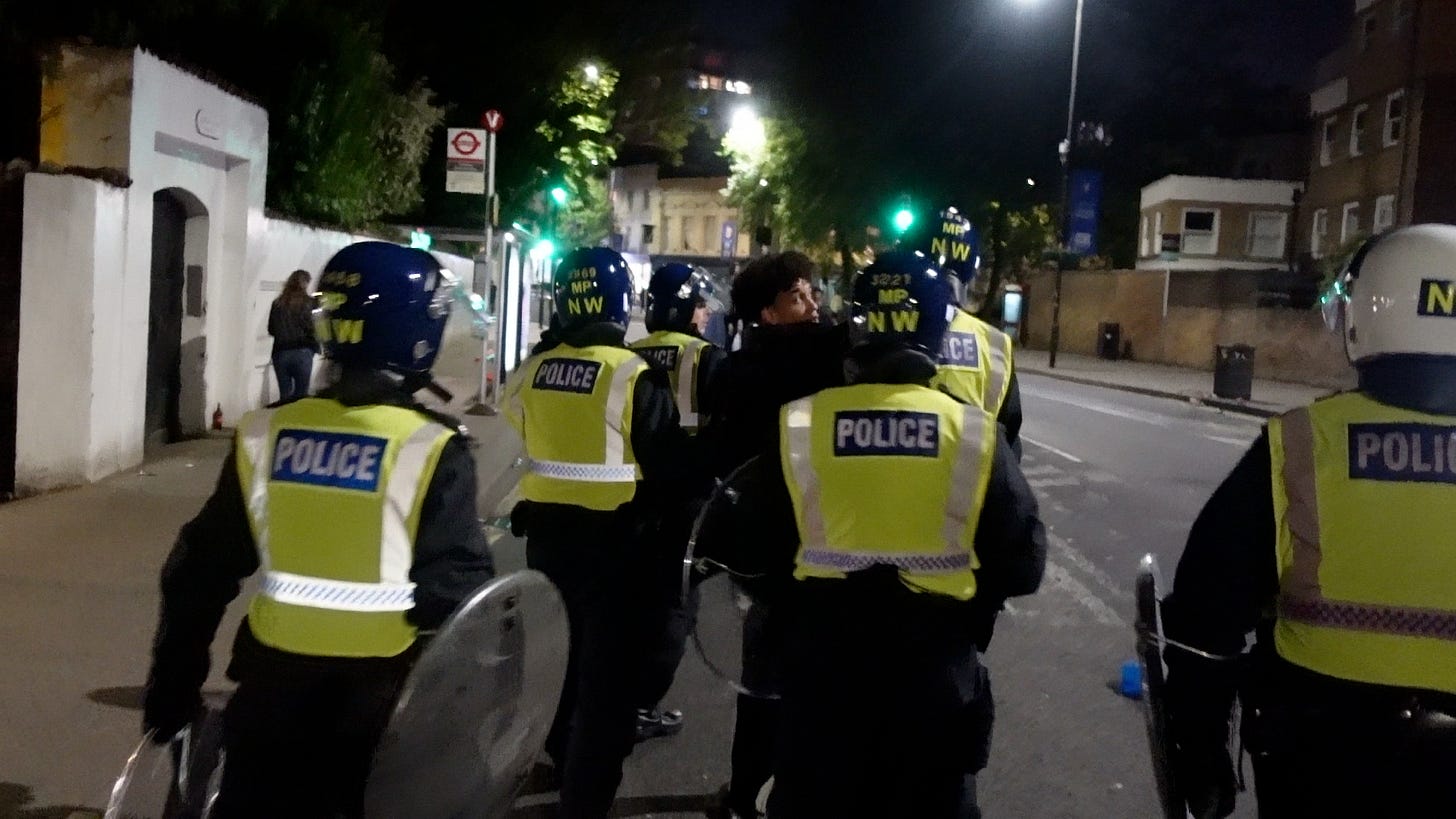 Metropolitan Police officers in helmets and hi-vis jackets on Fulham Road, London, at night, 30 May 2021. Metropolitan Police officers in helmets and hi-vis jackets on Fulham Road, London, at night, 30 May 2021.