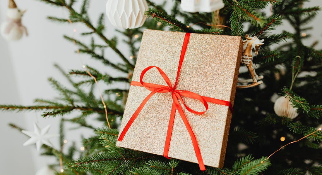 A brown present with red ribbon on top of a Christmas tree with red ribbon A brown present with red ribbon on top of a Christmas tree with red ribbon