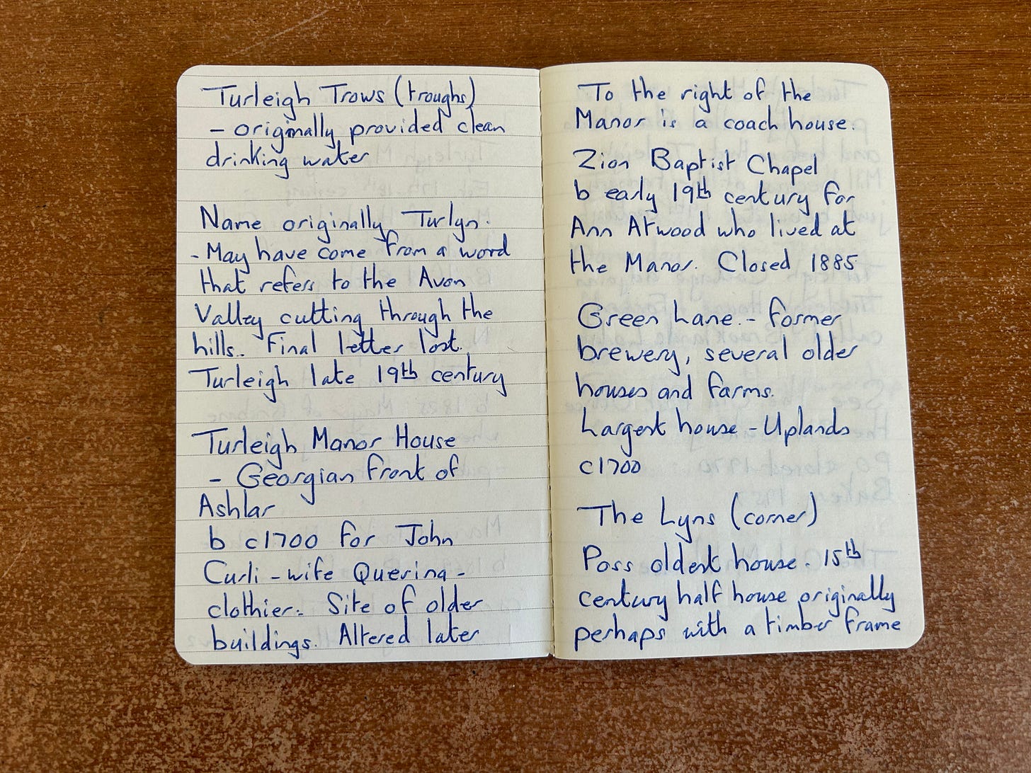 An opened notebook with handwritten text. Lying open on a desk.